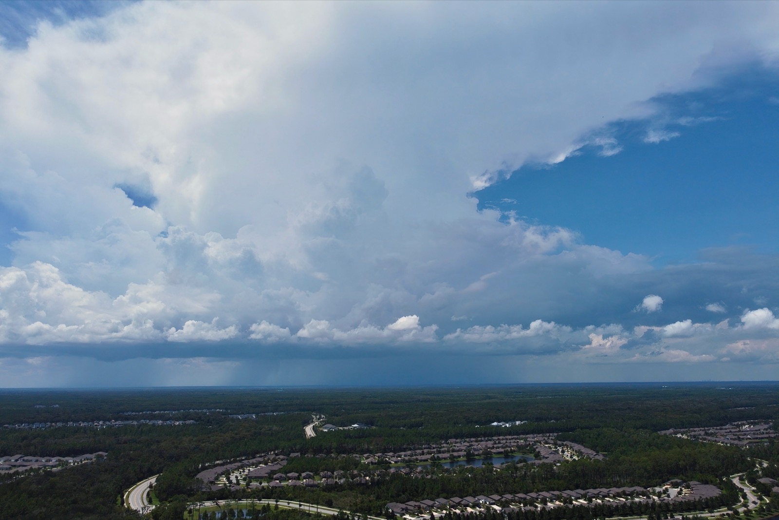 Arial view of an isolated rain storm in the distance over a suburban landscape